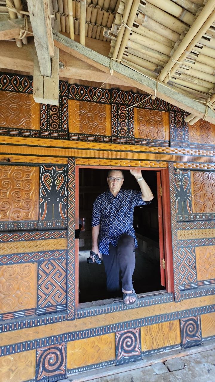 Pengunjung di pintu bangunan kayu berukir.