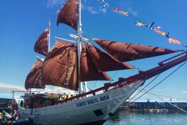 Kapal layar kayu dengan layar berwarna merah.