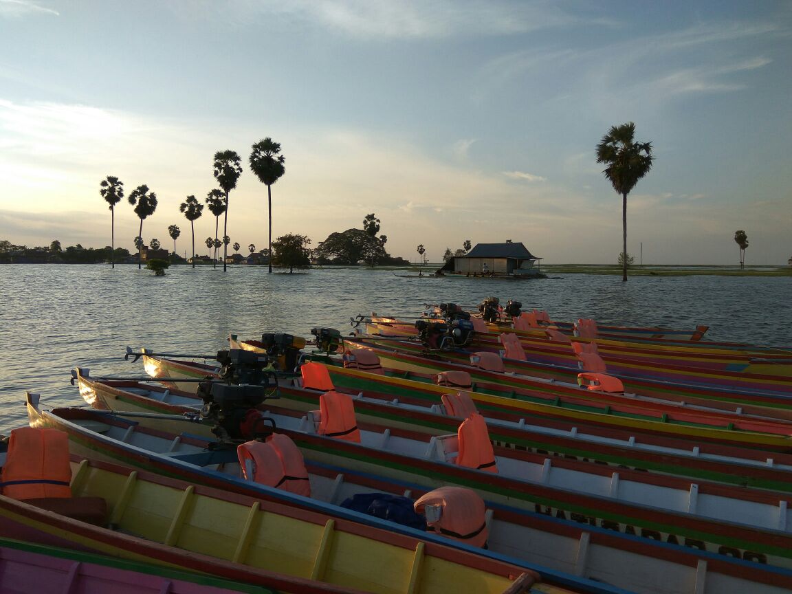 Perahu-perahu berwarna di tepi danau saat senja.