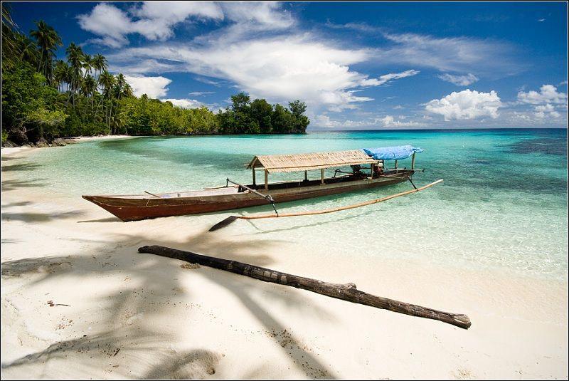 Perahu bercadik di pantai berpasir putih.