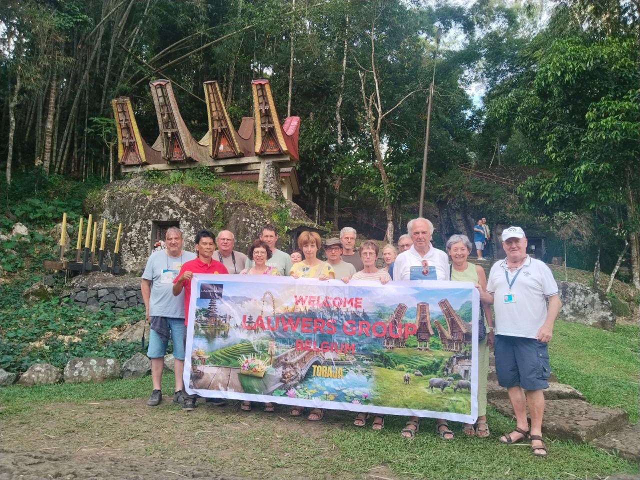 The Lauwers group from Belgium holding a welcome banner in front of a traditional Toraja site